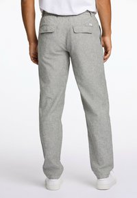 Pantalon en lin gris avec une coupe décontractée, présentant deux poches arrière en applique et un tissu texturé. Assorti à des baskets blanches.
