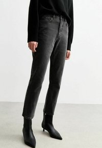 Svarta denimjeans med rak ben-design, som har fem fickor, bälteshällor och kontrasterande sömmar, kombinerat med svarta spetsiga ankelstövlar.