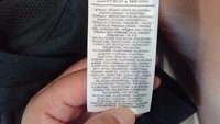 Étiquette d'entretien d'un vêtement, comportant plusieurs langues. Elle indique 92 % de polyester et 8 % d'élasthanne, avec des instructions d'entretien répertoriées.