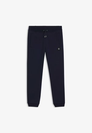 Pantalones de chándal azul marino hechos de una tela suave. Cuentan con una cinturilla elástica con cordón, bolsillos laterales y un parche con logo en el muslo.
