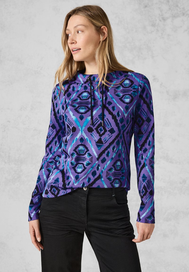 Langärmliger Hoodie mit einem lila geometrischen Muster und blauen sowie schwarzen Akzenten. Hergestellt aus weichem, dehnbarem Stoff mit einer lockeren Passform.