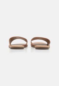 Brune lær sandaler med to buede stropper og flade såler. Tekstureret fodseng og minimalistisk design. Ingen yderligere metaldele eller accenter.