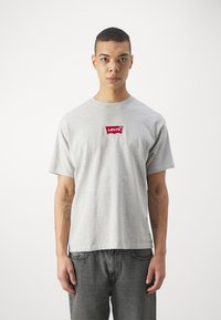 Grå bomulds T-shirt med rund halsudskæring og korte ærmer, med et rødt broderet Levi's-logo i midten.