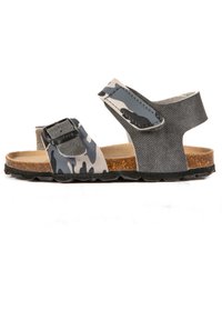 Sandales camouflage noires et grises avec des sangles réglables, semelle en liège et semelle en caoutchouc texturé, présentant un design ouvert et épuré.