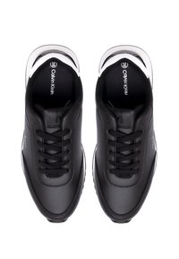 Czarne skórzane sneakersy z sznurowanym wzorem, charakteryzujące się smukłym kształtem, srebrnymi akcentami na pięcie oraz logo na wewnętrznej podeszwie.