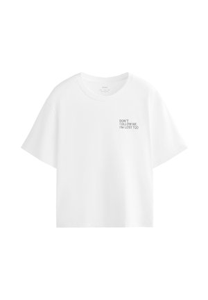 T-shirt blanc à manches courtes avec col rond et petit texte noir en haut à gauche indiquant, "NE ME SUIVEZ PAS, JE SUIS PERDU AUSSI."