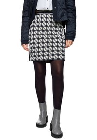 Skirt with a black and white geometric pattern, knee-length, paired with black tights and gray ankle boots with a chunky sole.