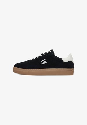 Sneaker din suede negru cu accent alb pe călcâi, șireturi albe și talpă din cauciuc de tip gumă. Prezintă un mic logo brodat pe lateral.