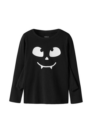 Chemise noire à manches longues avec un visage de dessin animé blanc présentant de grands yeux, un petit nez et deux crocs pointus à l'avant.
