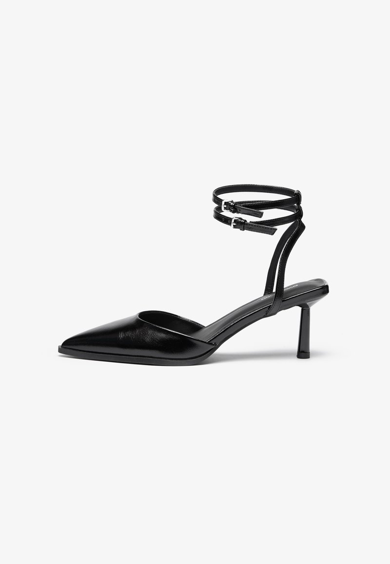 Chaussure à talon haut en cuir noir avec un bout pointu et une bride de cheville. Présente un design épuré et un talon fin de 5 cm. Texture lisse.