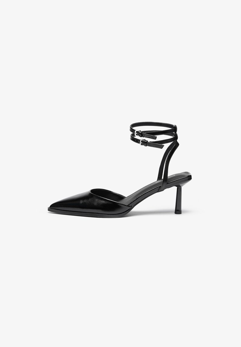 Chaussure à talon haut en cuir noir avec un bout pointu et une bride de cheville. Présente un design épuré et un talon fin de 5 cm. Texture lisse.