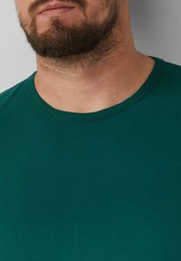 Groene katoenen T-shirt met een ronde halslijn en korte mouwen. Gladde textuur met minimale stikseldetails.