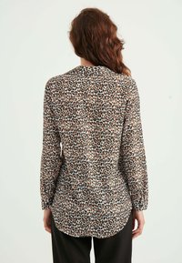 Langærmet skjorte i leopardmønster, lavet af let stof, med rund kant og en afslappet pasform. Farvepaletten inkluderer beige, sort og nuancer af brun.