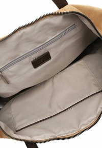 Brown suede bag interior features beige lining, a zippered pocket, and a flat compartment. Sturdy zipper and logo tag included.