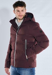 Bordeauxrote Steppjacke mit Kapuze, weißen Reißverschluss-Akzenten und Seitentaschen. Verfügt über ein gestepptes Design und ein Logo-Patch am Ärmel.