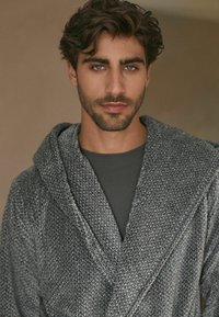 Grå tekstureret kimono med sjalskrave, i en blanding af mørke og lyse grå garn. Bæres over en mørkegrå top. Blødt, hyggeligt stof.