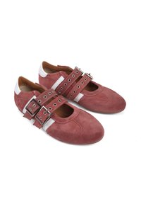 Czerwone zamszowe buty z białymi akcentami, otwarty czubek, podwójne paski na klamry i ozdobne przeszycia. Płaska podeszwa, zaokrąglony kształt.
