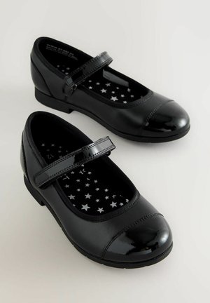 Melnas lakotas ādas kurpes ar apaļu purngalu, plakanu papēdi un siksniņu pāri pēdas vidum. Iekšējai pusei ir zvaigžņu raksts uz melna fona.