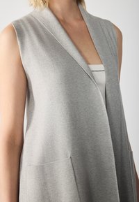 Gray sleeveless cardigan made of soft knit fabric, featuring a deep V-neck, two front pockets, and a relaxed fit.