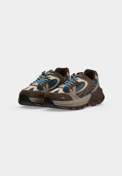 Paire de baskets marron, beige et bleues avec des lacets bleu clair et des semelles épaisses, placées côte à côte sur un fond uni.