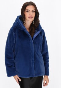 Giacca con cappuccio in pelliccia sintetica di colore blu intenso, caratterizzata da una texture leggermente lucida, chiusura con zip e vestibilità comoda con maniche lunghe.