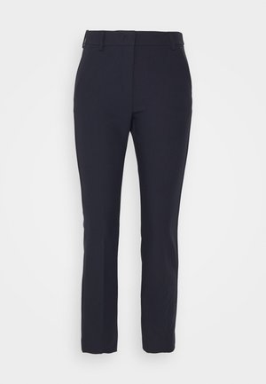 Laivastonsiniset naisten slim fit -housut vyölenkeillä ja etusauman yksityiskohdalla, esitetty yksiväristä valkoista taustaa vasten.