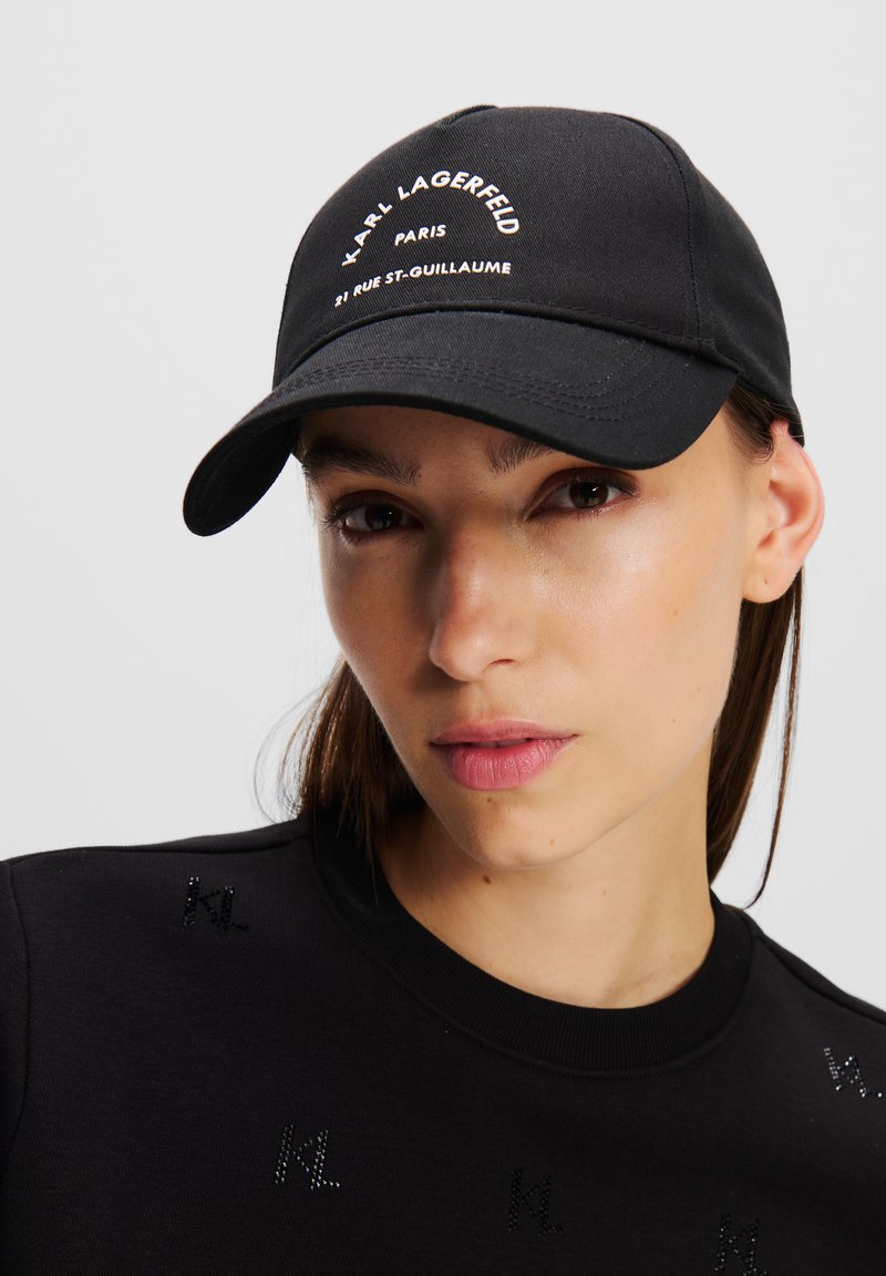Svart baseballkeps i bomull, med vit broderad text "Karl Lagerfeld Paris" och designelement på skärmen och kronan.