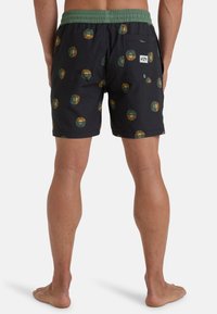 Costumi da bagno di colore blu navy con una cintura verde, caratterizzati da un motivo stampato di design circolari in verde e giallo. Include una tasca sul retro.