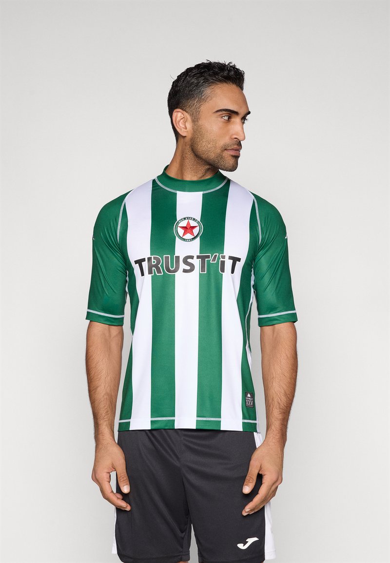 Zielono-biała koszulka sportowa w paski z krótkim rękawem, z napisem "TRUST'IT" i logo w kształcie gwiazdy. Noszona z czarnymi szortami.