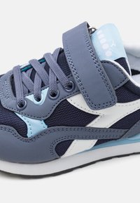 Scarpa sportiva blu con un mix di rete e pelle sintetica, dettagli bianchi, cinturino regolabile e suola testurizzata per una migliore aderenza.