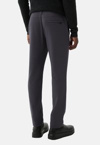 Grijze joggingbroek met een gladde textuur, voorzien van een ritszak aan de achterkant en een slim fit, gecombineerd met zwarte schoenen.