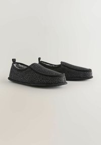 Pantofole nere con texture, dotate di un morbido rivestimento interno, suola flessibile e punta arrotondata. Presentano linguette per indossarle facilmente.