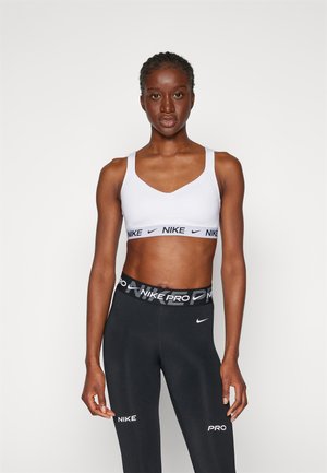 White sports bra with Nike logo, featuring a v-neck and wide straps, paired with black leggings that have a logo waistband and side accents.