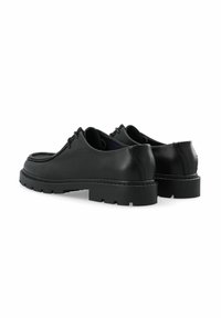 Chaussures en cuir noir avec une semelle en caoutchouc épaisse et texturée, bout rond et système de laçage traditionnel. Coutures décoratives le long du bord.