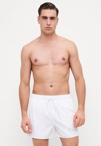 Shorts de baie albe cu talie cu șnur, textură netedă și un detaliu logo subtil în colțul din stânga jos.