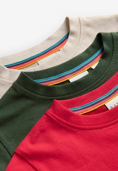 Tres camisetas de cuello redondo en beige, verde y rojo, con coloridos acentos a rayas en los cuellos y una textura de algodón suave.