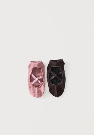 Par de calcetines de corte bajo estilo ballet, uno rosa y otro marrón oscuro, cada uno con correas elásticas cruzadas en la parte superior, colocados planos sobre fondo blanco.