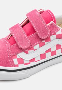 Scarpa in suede rosa e tessuto con cinturini in Velcro, motivo a scacchiera, logo bianco e suola nera. Presenta una parte superiore testurizzata e accenti a contrasto.
