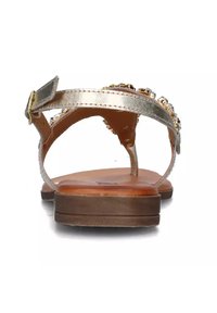 Sandal flat con una fascia metallica dorata, impreziosita da perline trasparenti. Sottopiede sintetico marrone e suola bassa in gomma marrone.