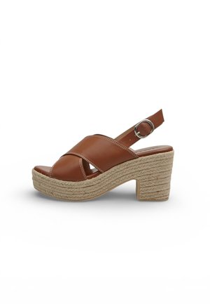 Sandalo slingback in pelle marrone con cinturini incrociati, tacco piattaforma intrecciato e fibbia argentata su sfondo bianco.