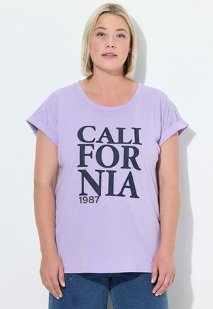 Vaaleanlila t-paita, jossa on käärityt lyhyet hihat ja rohkeaa mustaa tekstiä "CALIFORNIA 1987" rentoa fonttia käyttäen. Pehmeää kangasta, rento malli.
