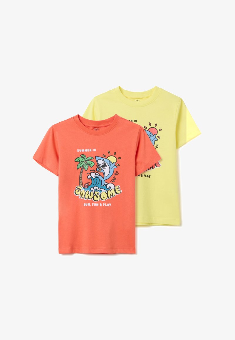 Dos camisetas de algodón: una de color coral con un diseño de un tiburón de dibujos animados y una palmera, la otra amarilla con gráficos similares, de mangas cortas y cuello redondo.