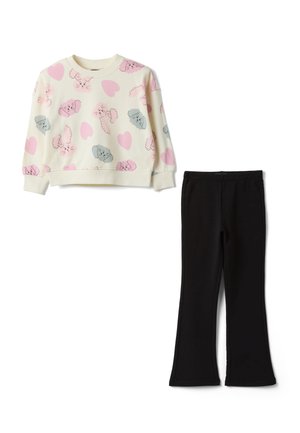 Sweat-shirt crème à manches longues avec des têtes de chiens roses et grises et des cœurs, assorti à un pantalon noir évasé uni.