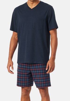Navy V-neck t-shirt with pocket, paired with plaid shorts featuring red and blue grid patterns on a dark background. Cotton material.