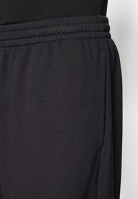 Svarte sweatpants med blødt stof, elastisk talje og sidelommer med en afslappet pasform, designet til komfort og bevægelsesfrihed.