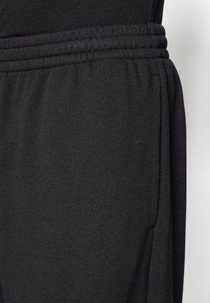 Black sweatpants featuring a soft fabric, elastic waistband, and side pockets with a relaxed fit, designed for comfort and ease of movement.