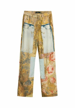 Trousers with tan and floral print, featuring large blue rectangular patches and safety pin details on front pockets and legs.