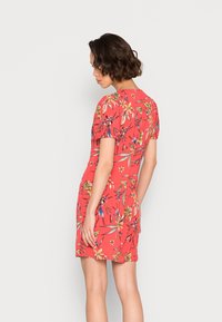 Vestido floral vermelho com mangas curtas e volumosas, apresentando um padrão vibrante de flores amarelas e azuis, textura lisa e silhueta ajustada.