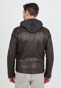 Ruskea nahkatakki, jossa on kiinteä harmaa huppari. Ominaisuuksiin kuuluu sileä pinta, olkasaumat ja napsautettavat napit. Takaa otettu näkymä.