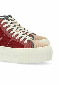 Baskets plateforme avec un mélange de velours côtelé rouge, beige et vert, dotées de semelles en caoutchouc blanc texturé et de lacets contrastants.